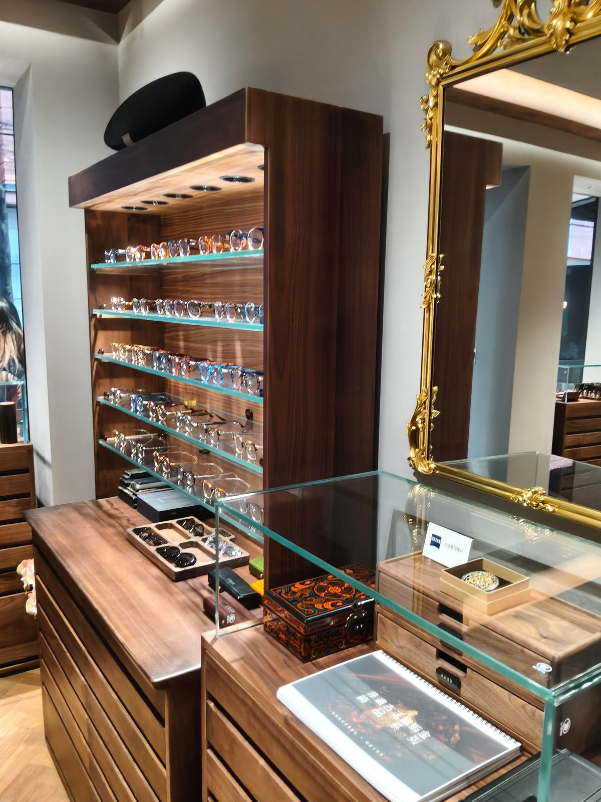 Walnut eyewear display cabinet with gold mirror